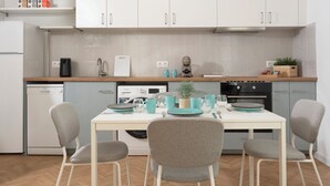 Une cuisine moderne avec des meubles blancs, un plan de travail en bois et une table à manger agrémentée de vaisselle turquoise et blanche.