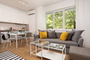 Una sala de estar moderna con un sofá gris, una mesa de centro y un comedor con una mesa y sillas.