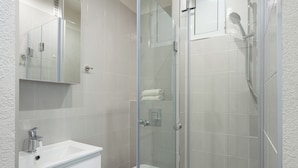 Une salle de bain moderne avec une douche à parois de verre, un lavabo blanc et des toilettes.