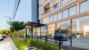 Un bâtiment moderne doté d’une façade en verre, d’un parking couvert et d’une pelouse bien entretenue.