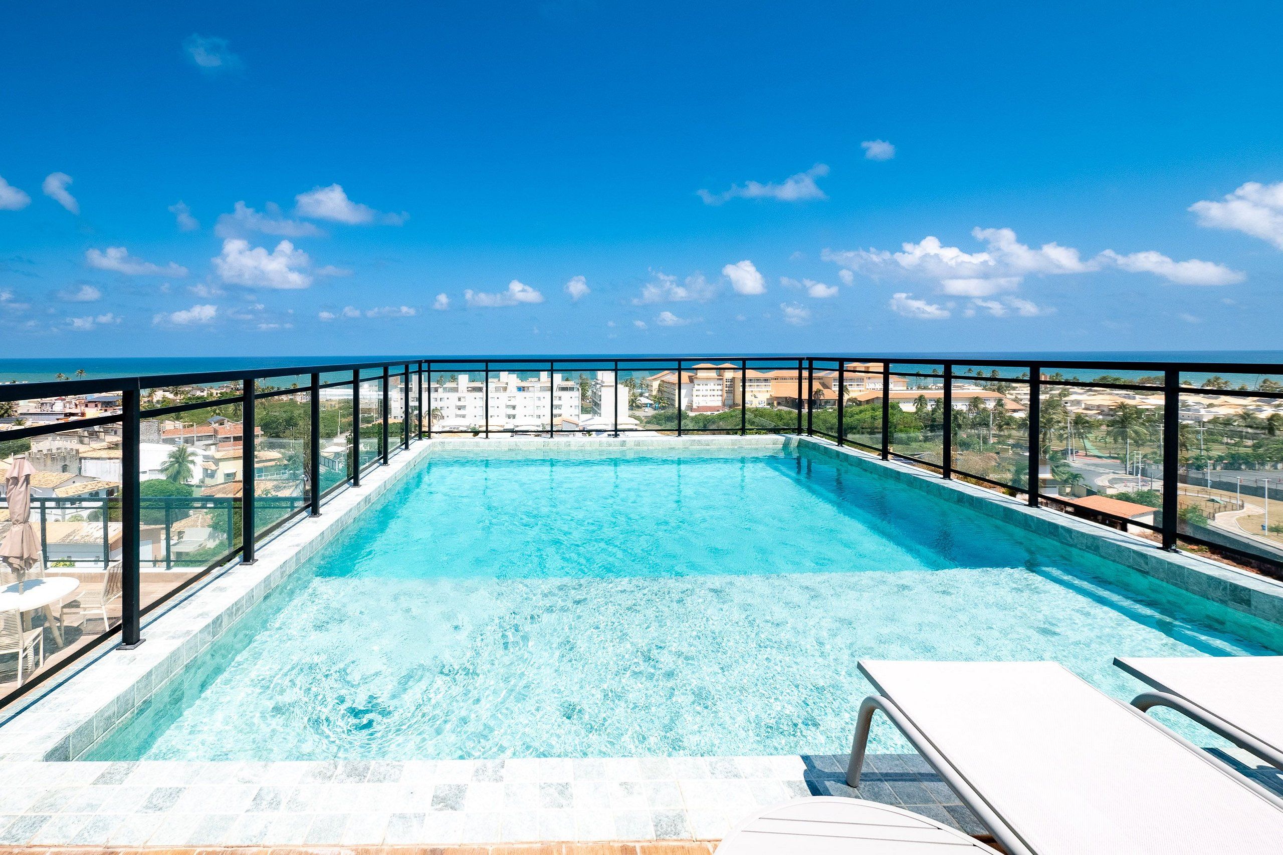 Une piscine à débordement située sur le toit, offrant une vue dégagée sur les gratte-ciel de la ville et l’océan.