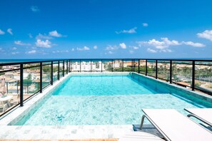 Une piscine à débordement située sur le toit, offrant une vue dégagée sur les gratte-ciel de la ville et l’océan.