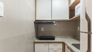 Egy kompakt konyha beépített tűzhellyel, mikrohullámú sütővel és hűt őszekrénnyel.