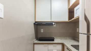 Uma cozinha compacta com fogão embutido, micro-ondas e geladeira.