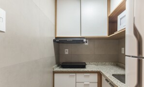 Una cocina compacta con estufa integrada, microondas y refrigerador.