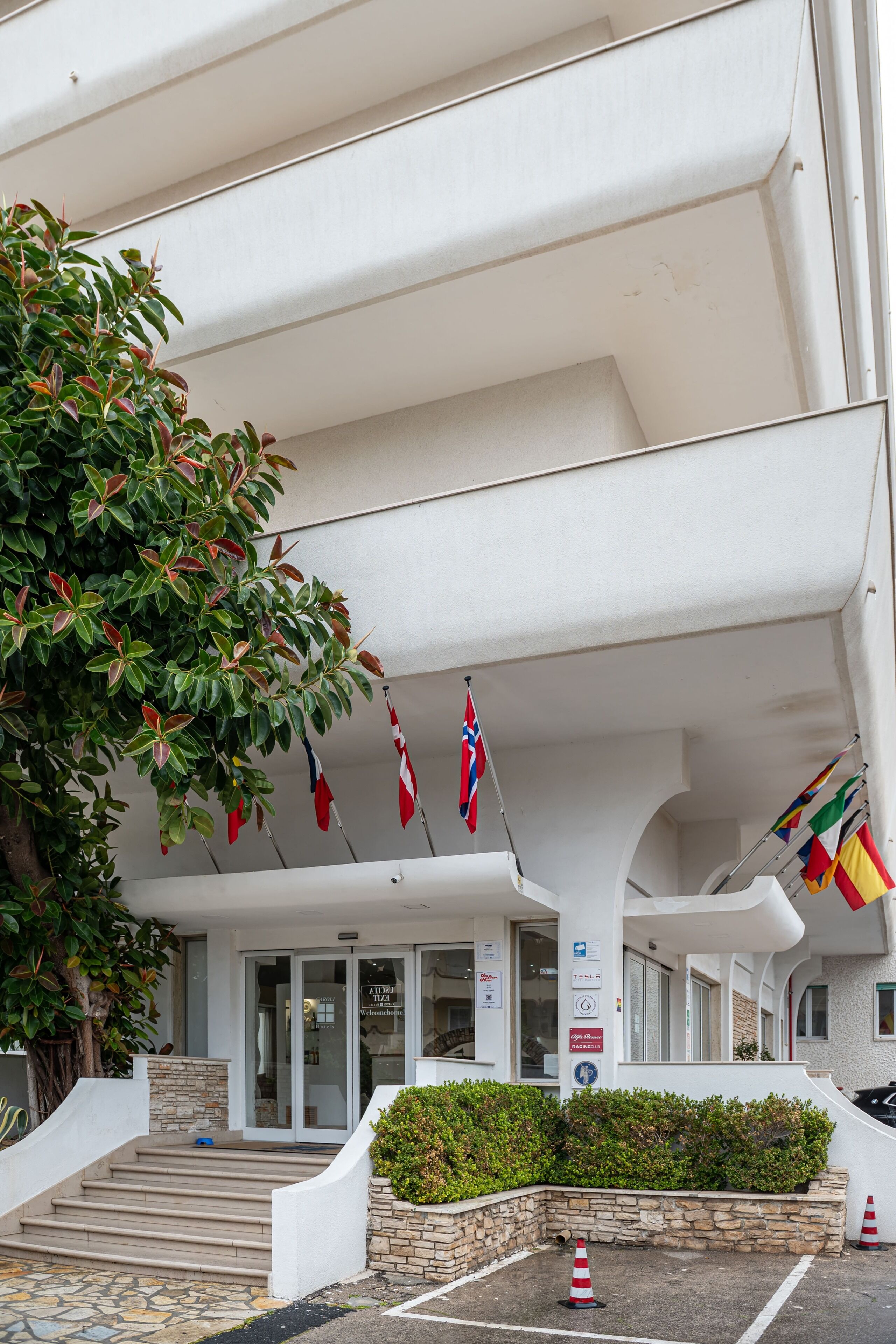 Un edificio con fachada blanca, una escalera que conduce a una puerta y varias banderas colgadas del techo.