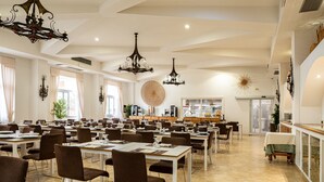A spacious dining area with multiple tables and chairs, a kitchen in the background, and decorative wall art. - Hotiday Gallipoli Centro (Gallipoli)