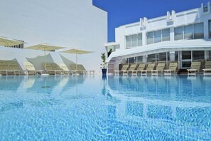 A swimming pool with lounge chairs and umbrellas, a modern building with large windows, and a clear blue sky. - Hotiday Gallipoli Centro (Gallipoli)