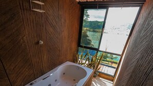 A modern bathroom with a freestanding bathtub, wooden walls, and a large window offering a scenic view. - Nativa Ecohotel - Laguna de San Diego (Samaná)