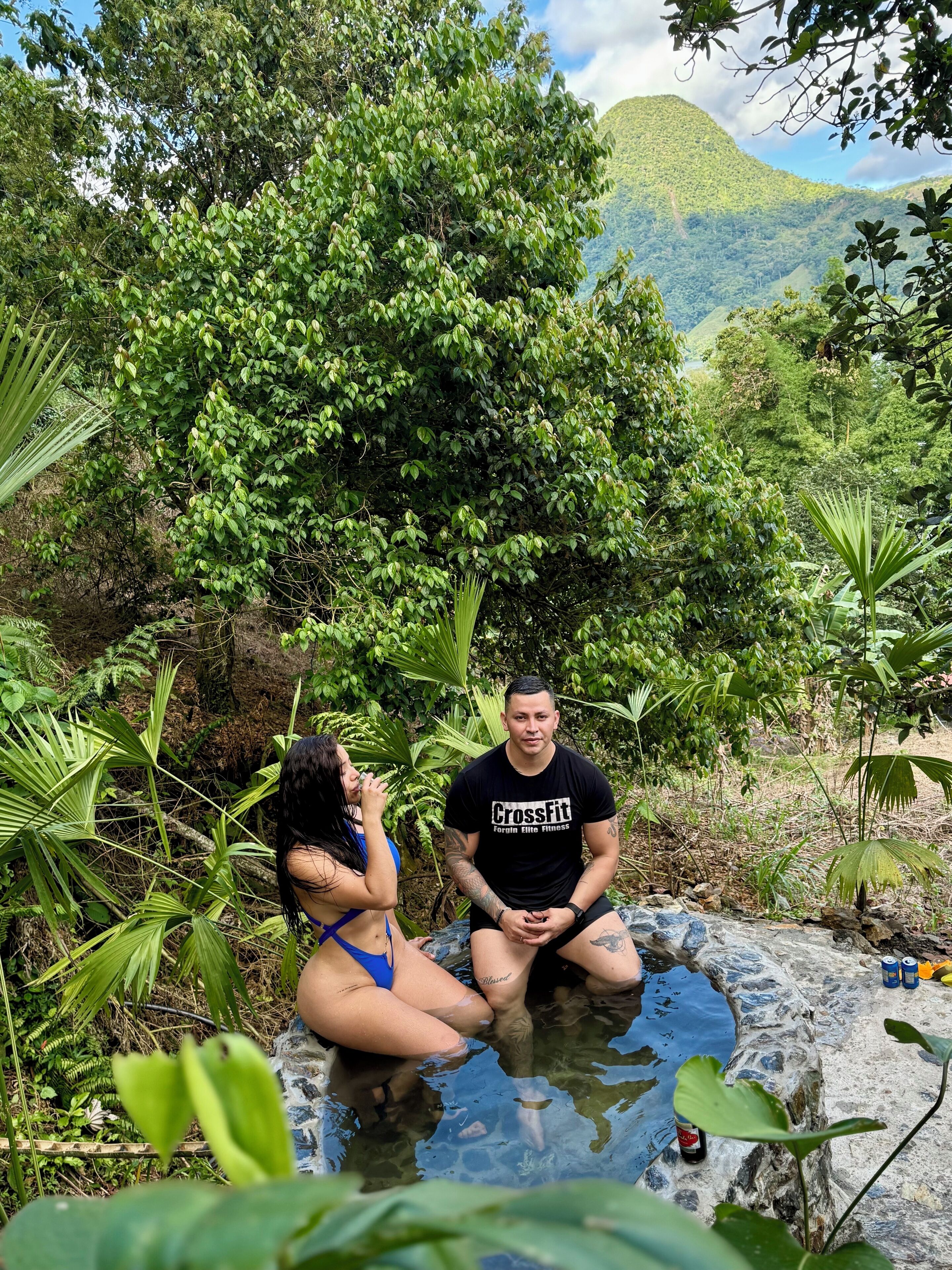 Two people sitting in a natural setting with a mountainous backdrop.