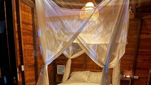 A wooden cabin room with a bed under a canopy. - Nativa Ecohotel - Laguna de San Diego (Samaná)