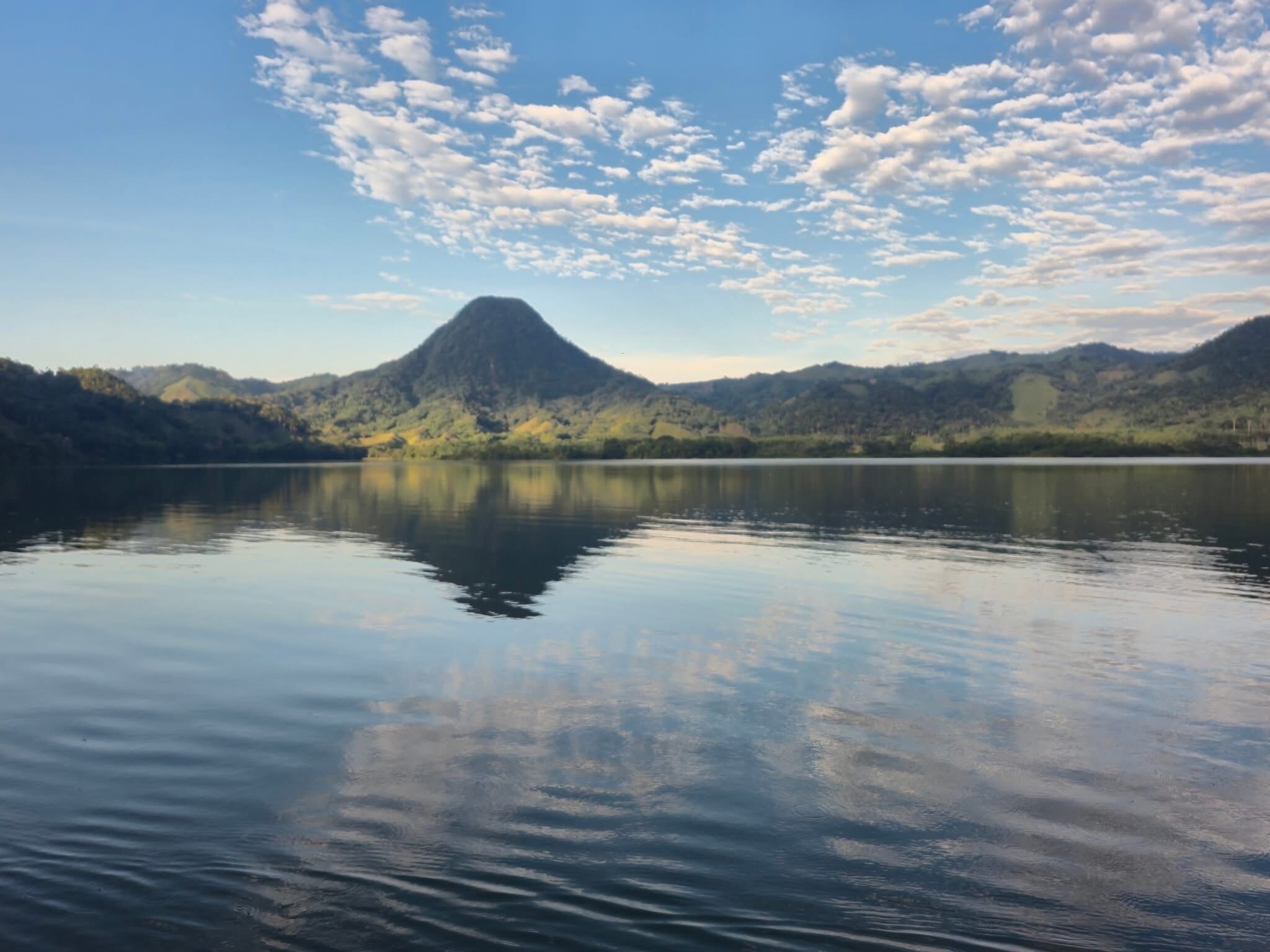 Un lago tranquilo con una montaña al fondo y un cielo despejado.
