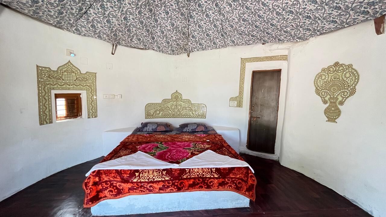 A bedroom with a bed, a door, and decorative wall patterns.