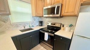 A kitchen with wooden cabinets, a stainless steel microwave, an oven, and a refrigerator.