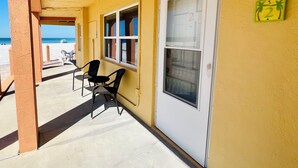 A covered outdoor area with a yellow wall, a door with a number, and two windows.