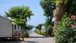 A row of mobile homes with a paved driveway leading to a beach. - ⛱️ Direct beach access - 4* campsite All-comfort mobile home + Covered terrace (Vias)