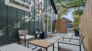 An outdoor patio with a table and chairs, a fan, and a wooden fence.