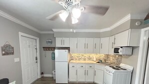 A compact kitchen with white cabinets, a refrigerator, a stove, and a microwave. - Boutique Stay on Clearwater Beach 1BR Suite w/full Kit
Unit 2 (Clearwater Beach)