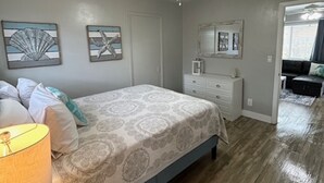 A bedroom with a bed, a nightstand, a lamp, a ceiling fan, and artwork on the walls. - Boutique Stay on Clearwater Beach 1BR Suite w/full Kit
Unit 2 (Clearwater Beach)