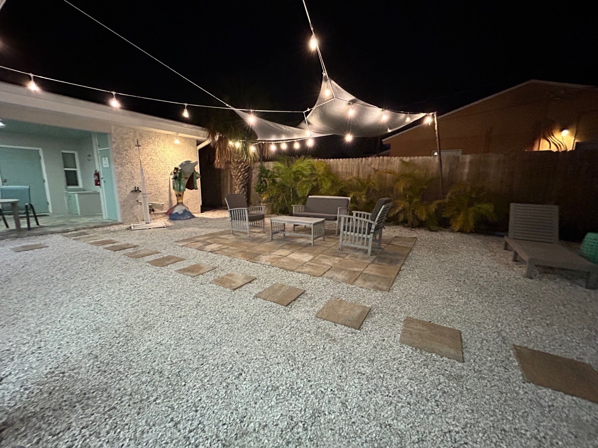 Un espace extérieur aménagé en terrasse, avec des sièges, un toit de chaume et des guirlandes lumineuses.
