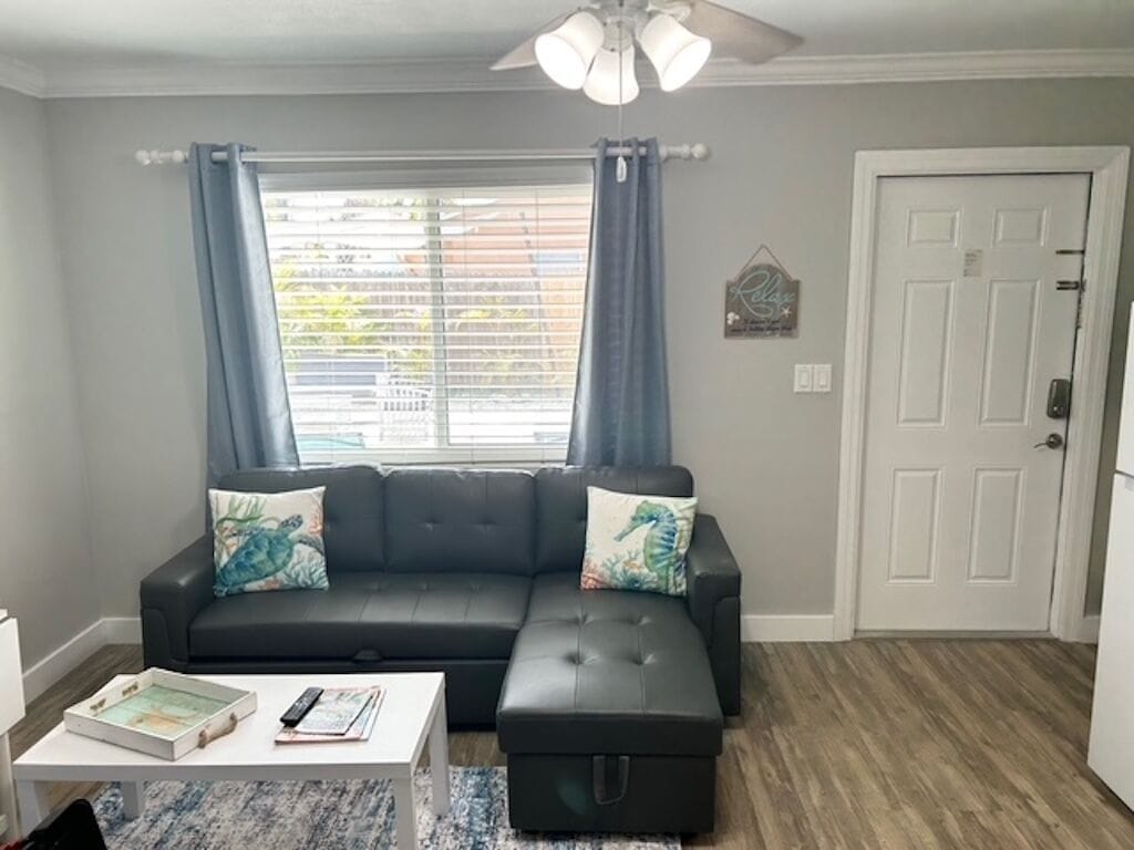 A living room with a sectional sofa, a coffee table, and a ceiling fan.