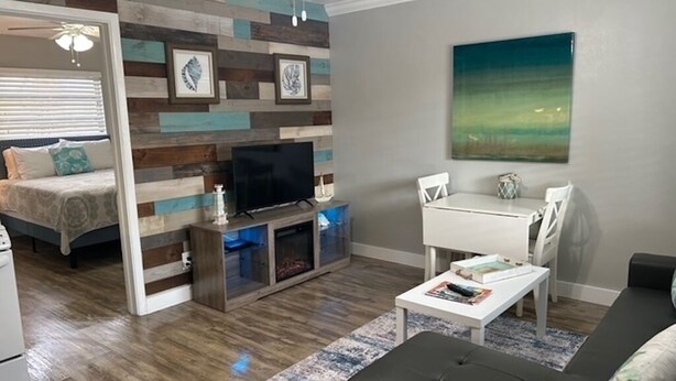 A living room with a sofa, coffee table, TV, and a painting on the wall. - Boutique Stay on Clearwater Beach 1BR Suite w/full Kit
Unit 2 (Clearwater Beach)