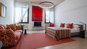 Une chambre moderne avec un canapé, un lit, une télévision et une grande fenêtre.