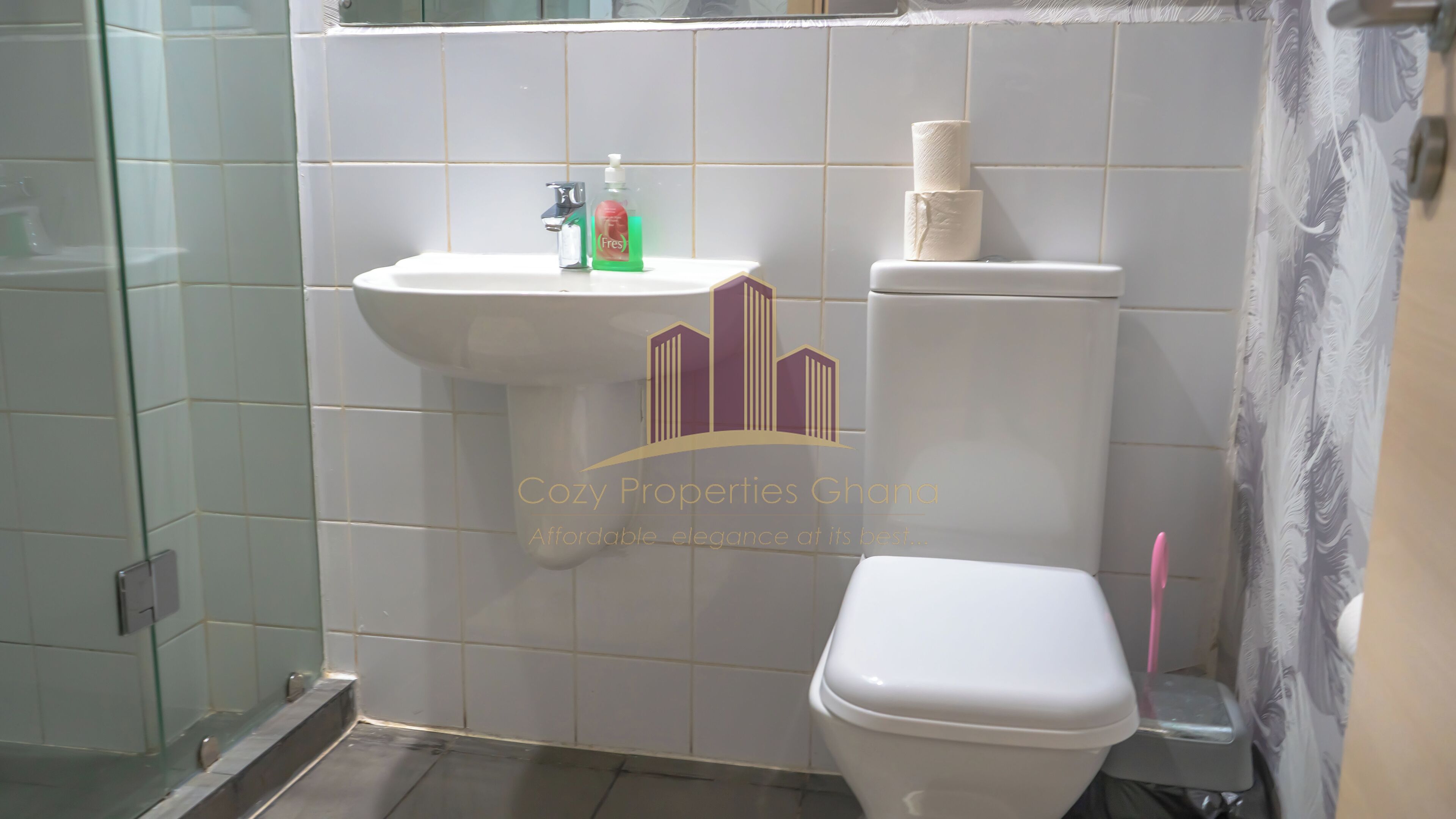Um banheiro com pia branca, vaso sanitário e box de vidro.