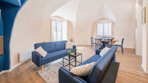 Un loft spacieux avec de hauts plafonds, un coin repas et un salon doté de canapés et d’une table basse.