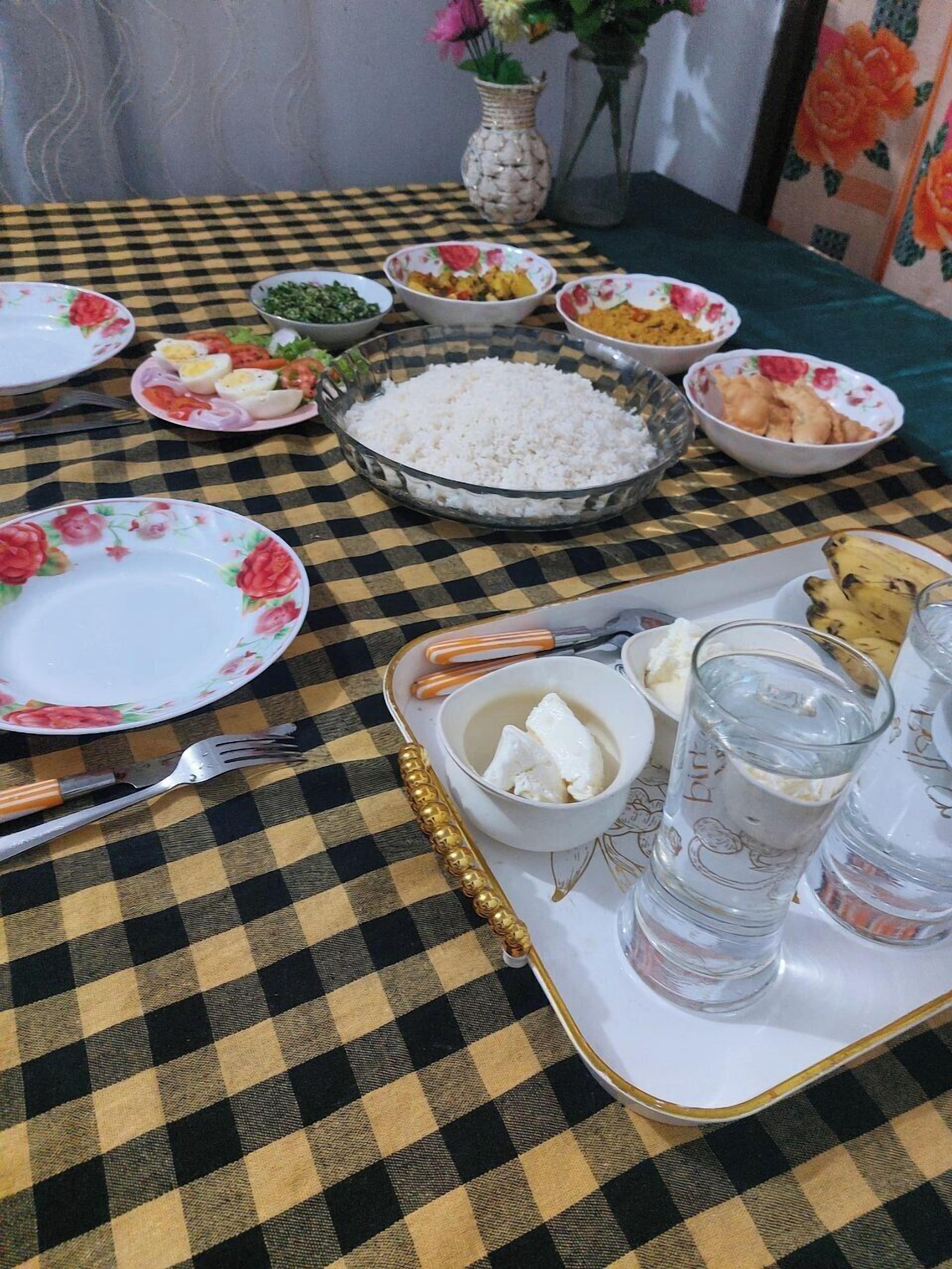 A table set with various dishes, including rice, eggs, and vegetables, along with glasses of water and a banana.