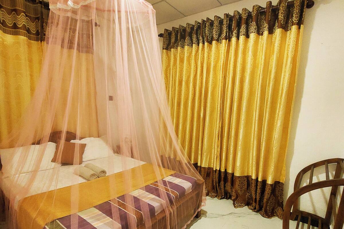Une pièce avec un lit, une chaise et un rideau.