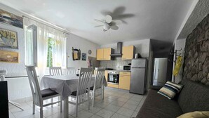 A modern kitchen with a dining area, a sofa, and a ceiling fan.