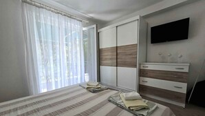 A bedroom with a bed, a wardrobe, a dresser, and a TV.
