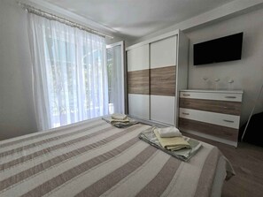 Une chambre à coucher avec un lit, une armoire, une commode et un téléviseur.