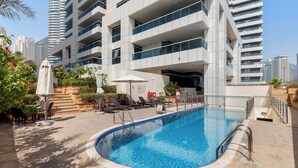 A modern building with a swimming pool, outdoor seating, and a staircase leading to the entrance. - Opal Tower Residences by CEG Group (Dubai)