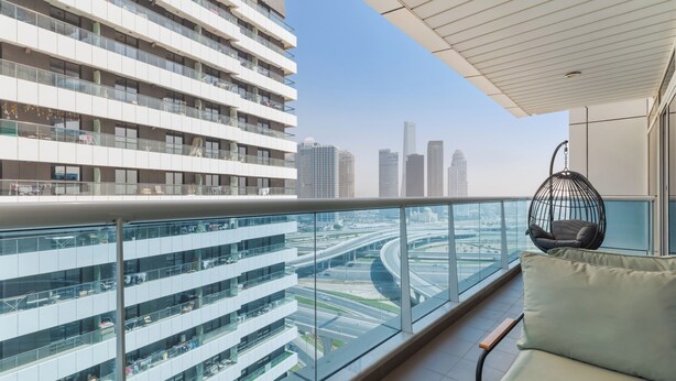 A modern hotel room with a balcony overlooking a cityscape and a highway. - Opal Tower Residences by CEG Group (Dubai)