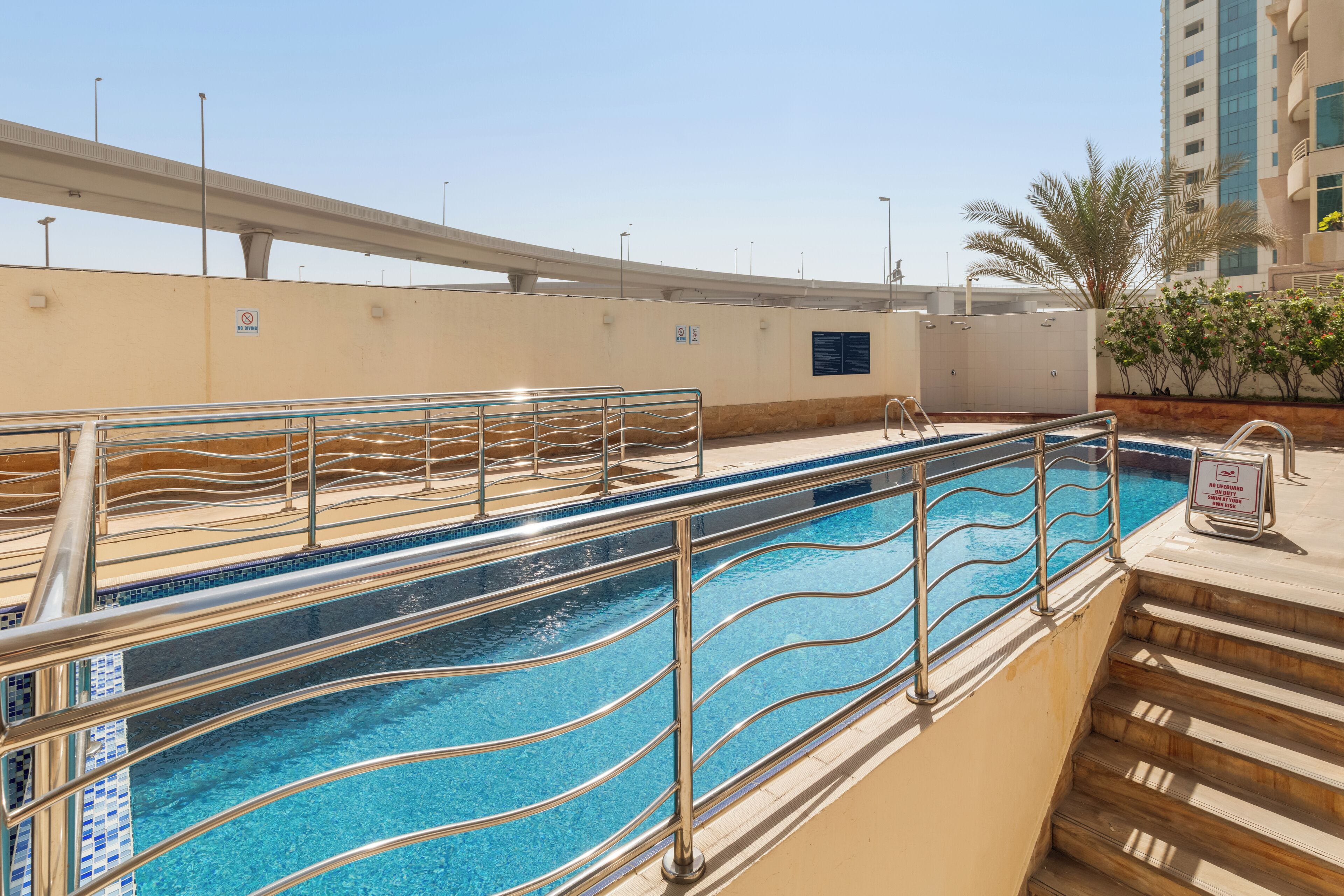 Una piscina con ringhiera metallica, un cartello che indica divieto di balneazione e una scala che scende.