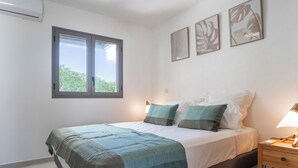 Ein Schlafzimmer mit Bett, Nachttisch, Lampe und Fenster.