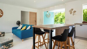 A modern kitchen with a wooden table and black chairs, a blue sofa with cushions, and a fan. - Villa Maeva, haven of peace just a few mn walk from the beach & a private pool (Saint-François)
