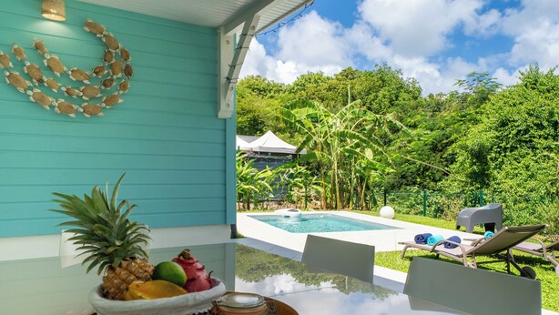 A poolside area with a table, chairs, and a view of a swimming pool and lush greenery. - Villa Maeva, haven of peace just a few mn walk from the beach & a private pool (Saint-François)