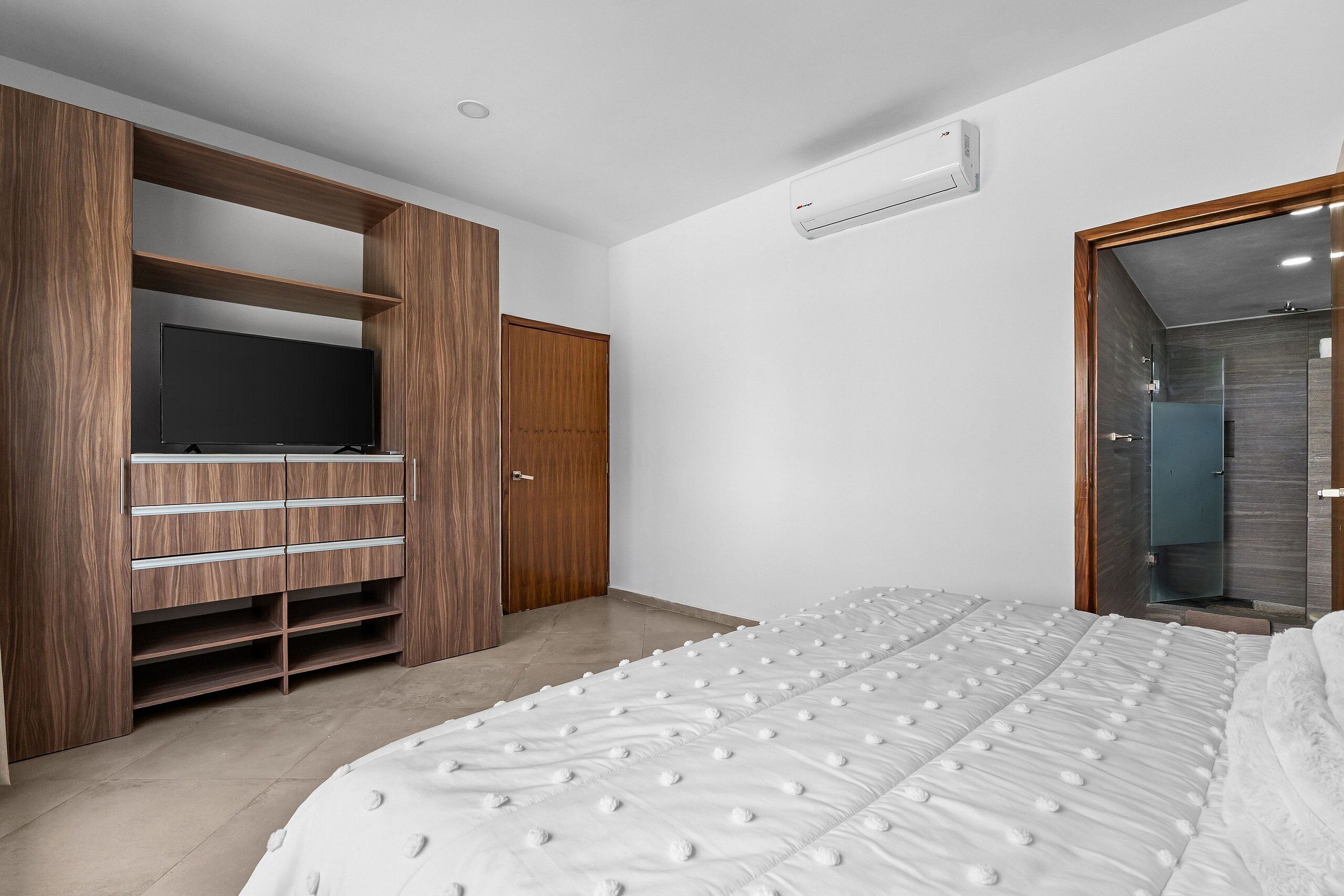 Un dormitorio con una cama grande, armario empotrado y televisión.