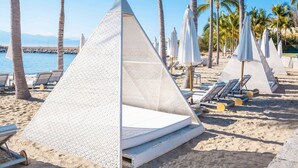 A beach with pyramid-shaped tents and lounge chairs. - Casa Oasis B-Nayar Gated Beach Club (La Cruz de Huanacaxtle)