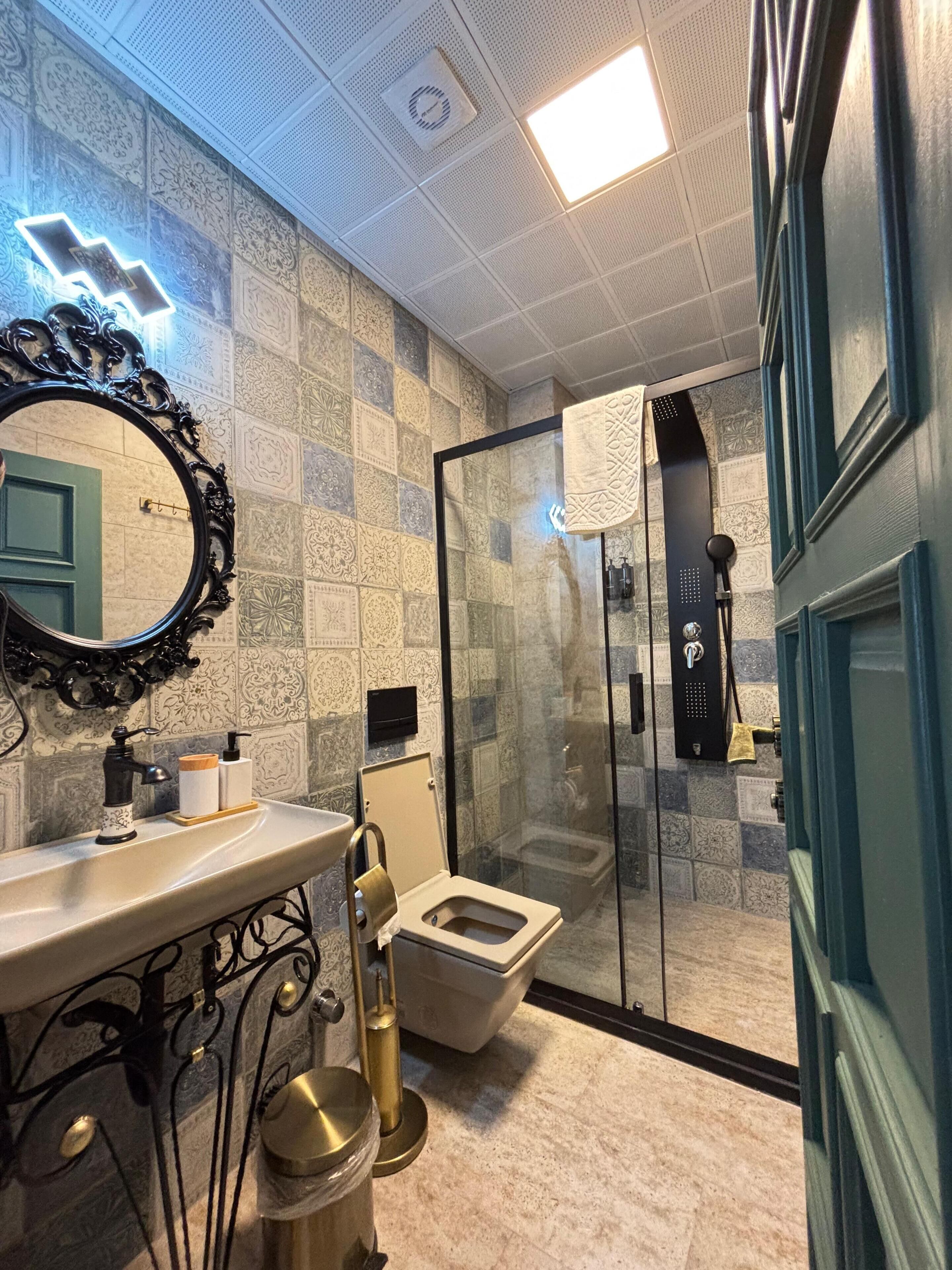 A bathroom with a toilet, sink, and shower area.