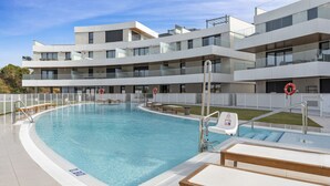 A modern hotel with a large swimming pool, outdoor seating, and a clear sky. - Venían Views 2BR Selwo Estepona (Málaga)