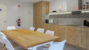 A modern kitchen with a wooden table and white chairs, a microwave, and a sink. - Private Garden - Deluxe Family Apartment (Porto)
