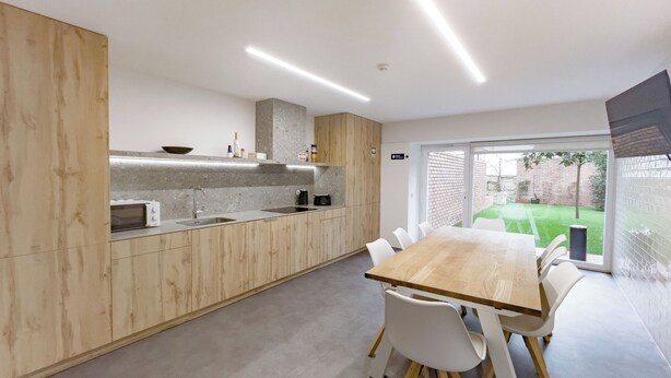 A modern kitchen with a wooden countertop, built-in appliances, and a dining area with a large table and chairs. - Private Garden - Deluxe Family Apartment (Porto)