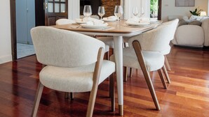 Een eetgedeelte met een ronde tafel voor vier personen, omringd door beklede stoelen.