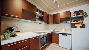 Een moderne keuken met houten kastjes, een inbouwoven, een vaatwasser en een aanrecht met een koffieapparaat.