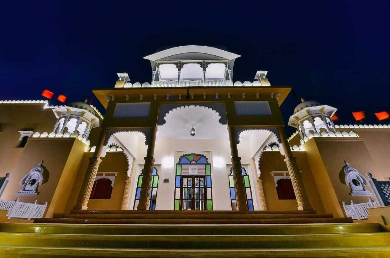 A traditional building with a central entrance, arched doorways, and a decorative roof.