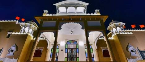 A traditional building with a central entrance, arched doorways, and a decorative roof.